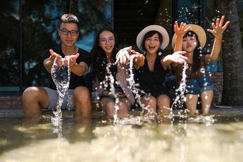 a group of young women sitting in the water at a fountain