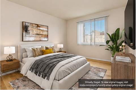 A bedroom with a large bed, a painting on the wall, and a window with blinds.