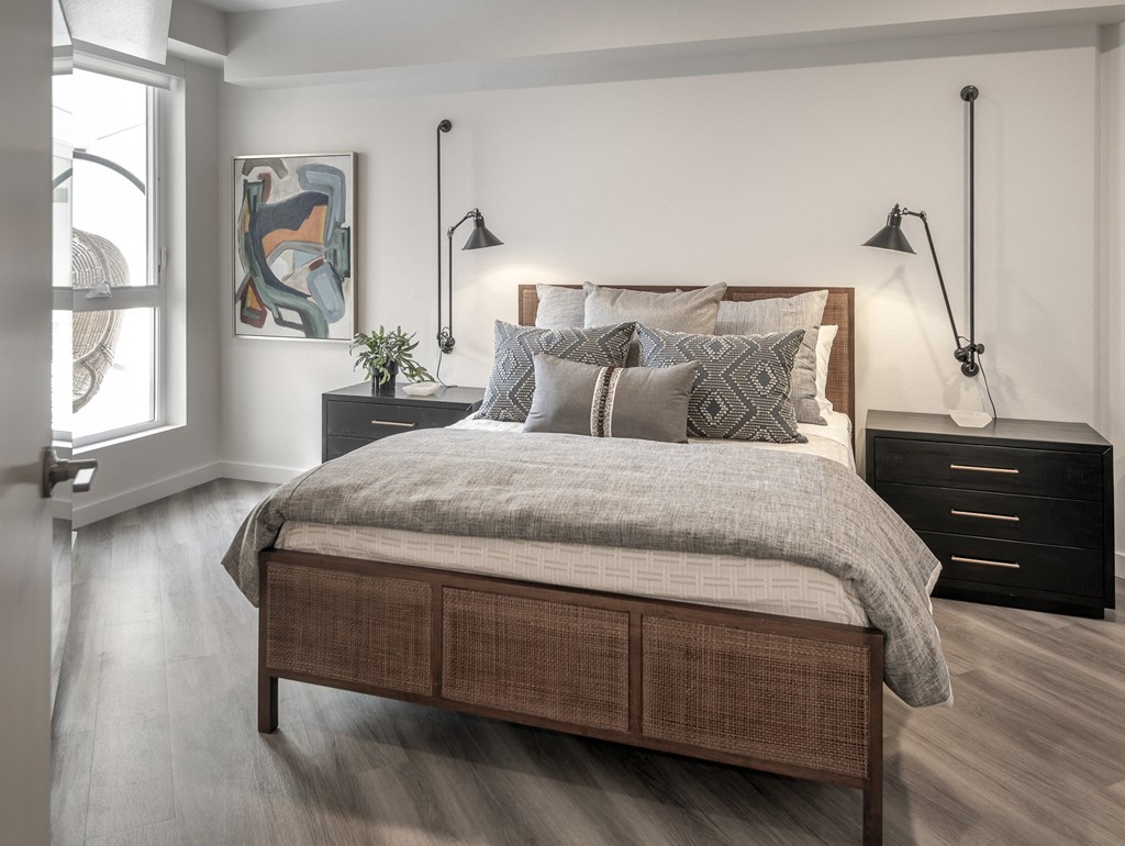 a bedroom with a bed and two nightstands and a window