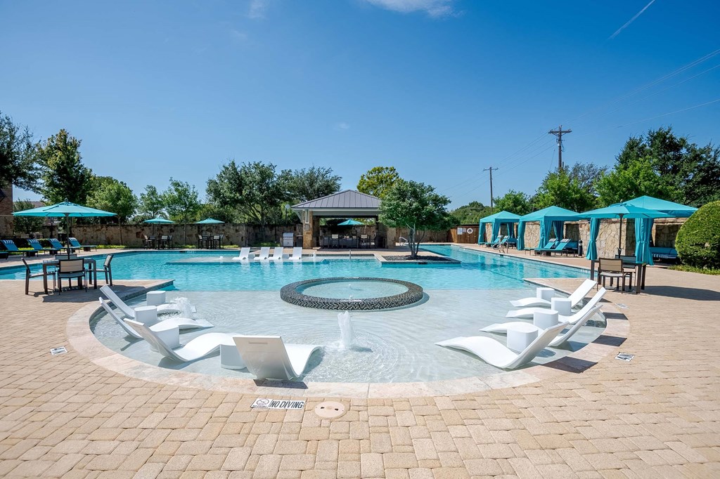 a resort style swimming pool with lounge chairs and umbrellas at Discovery at Craig Ranch, Texas
