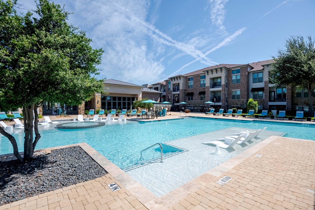 a large swimming pool with lounge chairs in front of an apartment building at Discovery at Craig Ranch, McKinney, 75070