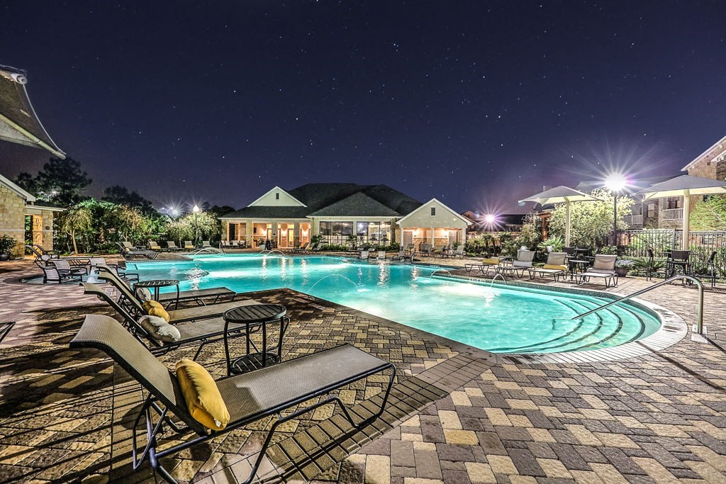 a swimming pool at night with chairs around it  at Waterstone at Cinco Ranch, Texas