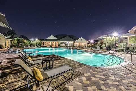 a swimming pool at night with chairs around it  at Waterstone at Cinco Ranch, Texas