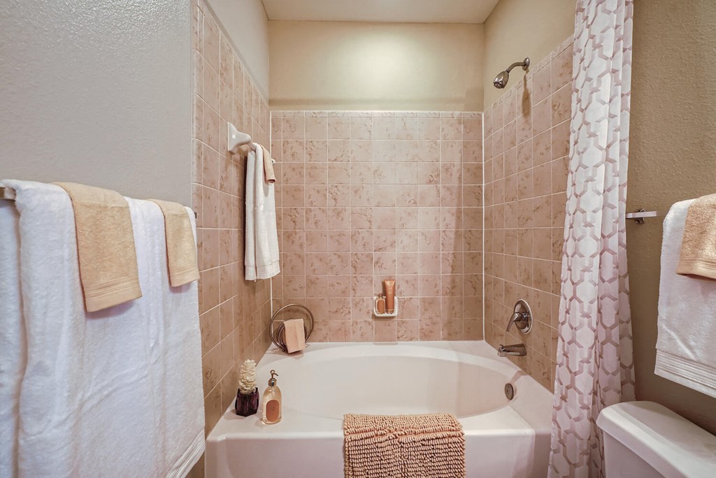 a bathroom with a large soaker tub and matching towels  at Grand Villas Apartments, Katy, TX