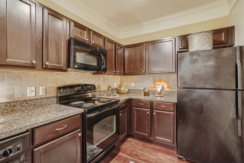 a kitchen with black appliances and granite counter tops  at Grand Villas Apartments, Texas