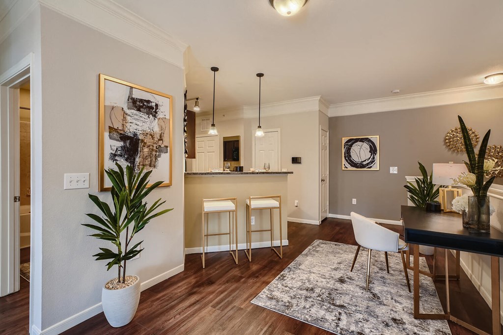 a living room and kitchen with a table and chairs  at Grand Villas Apartments, Katy, TX