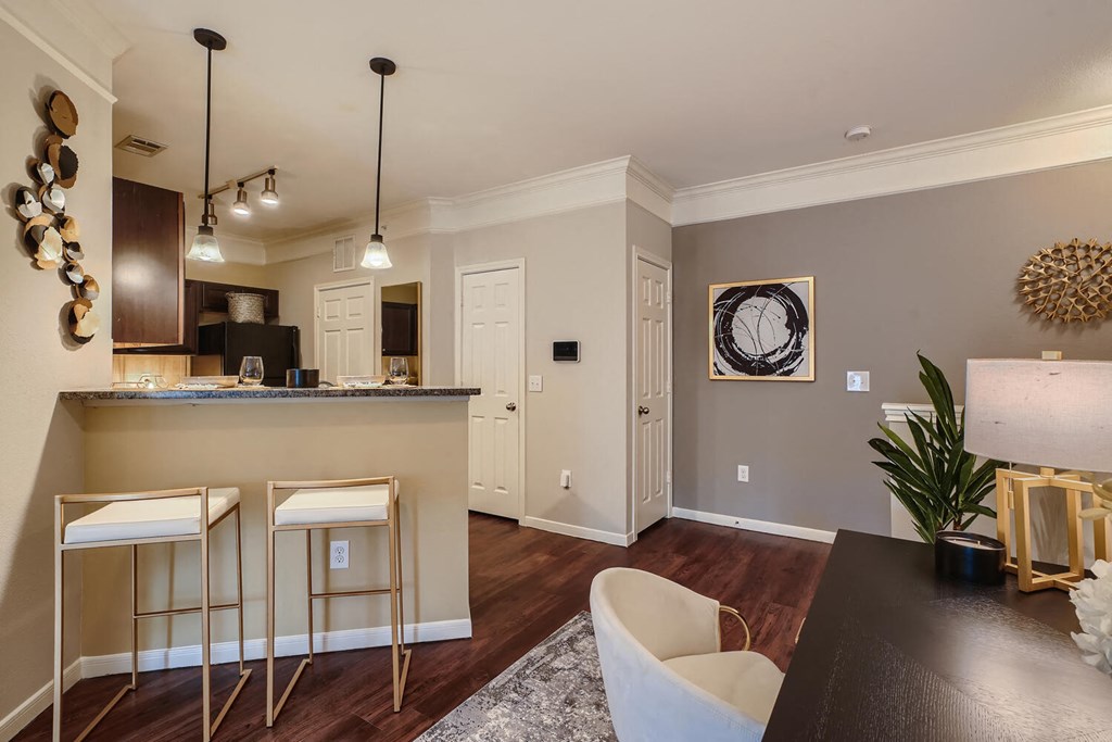 a kitchen and dining room with bar stools and breakfast bar  at Grand Villas Apartments, Texas