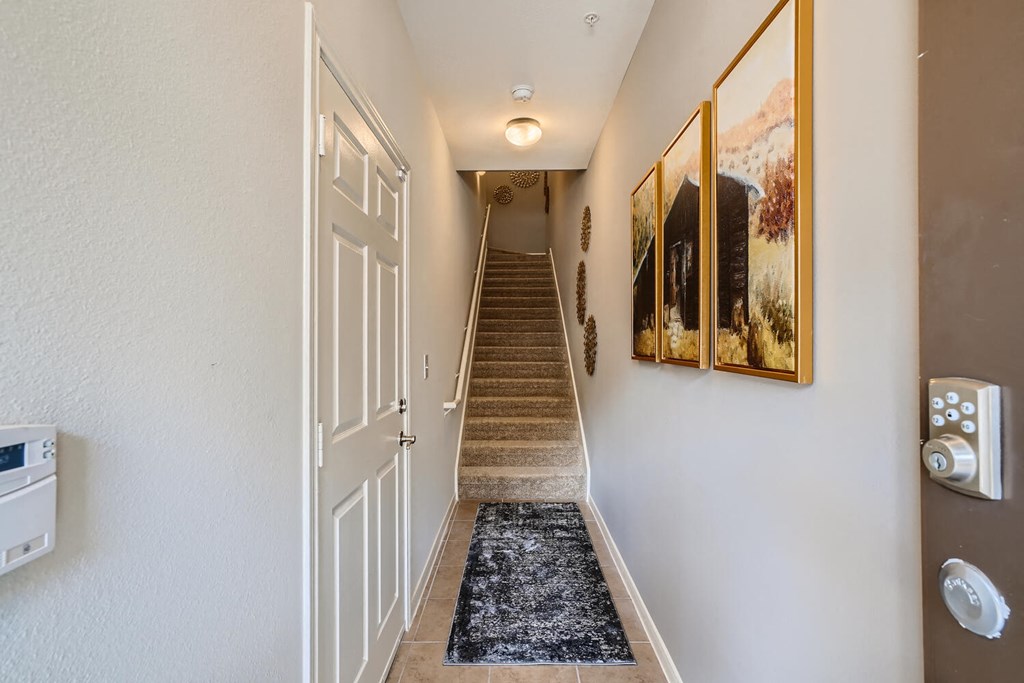 the entrance to a hallway with a staircase and a door leading up the stairs  at Grand Villas Apartments, Katy