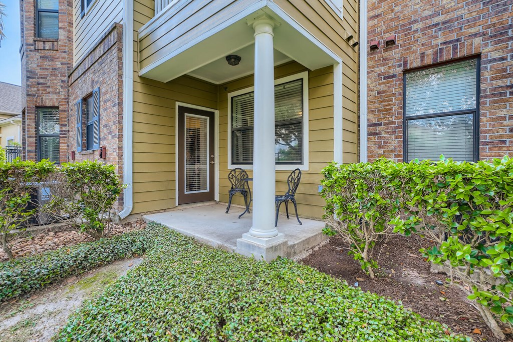 the front porch of a house with two chairs and a column  at Grand Villas Apartments, Katy
