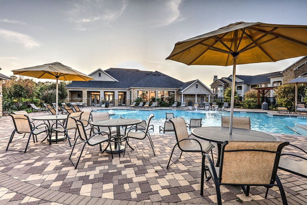 a resort style pool with tables and umbrellas at Waterstone at Cinco Ranch, Texas