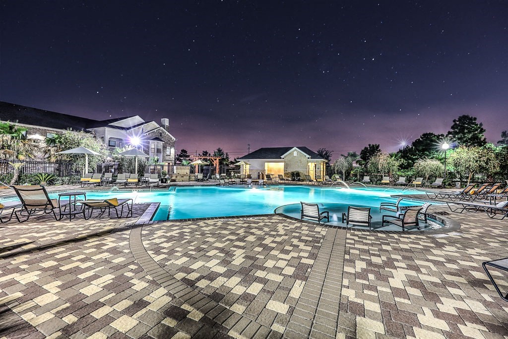 a large swimming pool at night with chairs around it  at Waterstone at Cinco Ranch, Katy, TX, 77450 