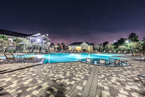 a large swimming pool at night with chairs around it  at Waterstone at Cinco Ranch, Katy, TX, 77450