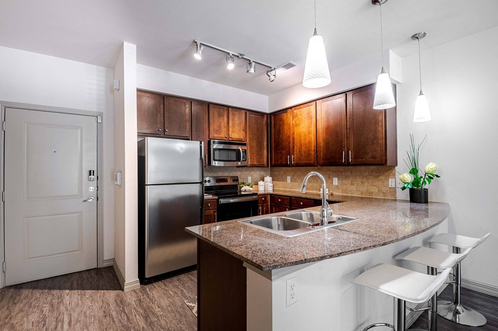 a kitchen with a granite counter top and a stainless steel refrigerator at Discovery at Craig Ranch, McKinney, TX