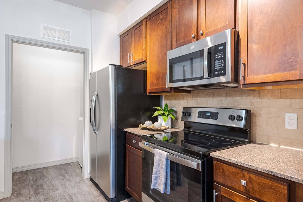a kitchen with stainless steel appliances and wooden cabinets at Discovery at Craig Ranch, McKinney, TX