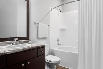 A bathroom with a white tub, sink, and toilet.
