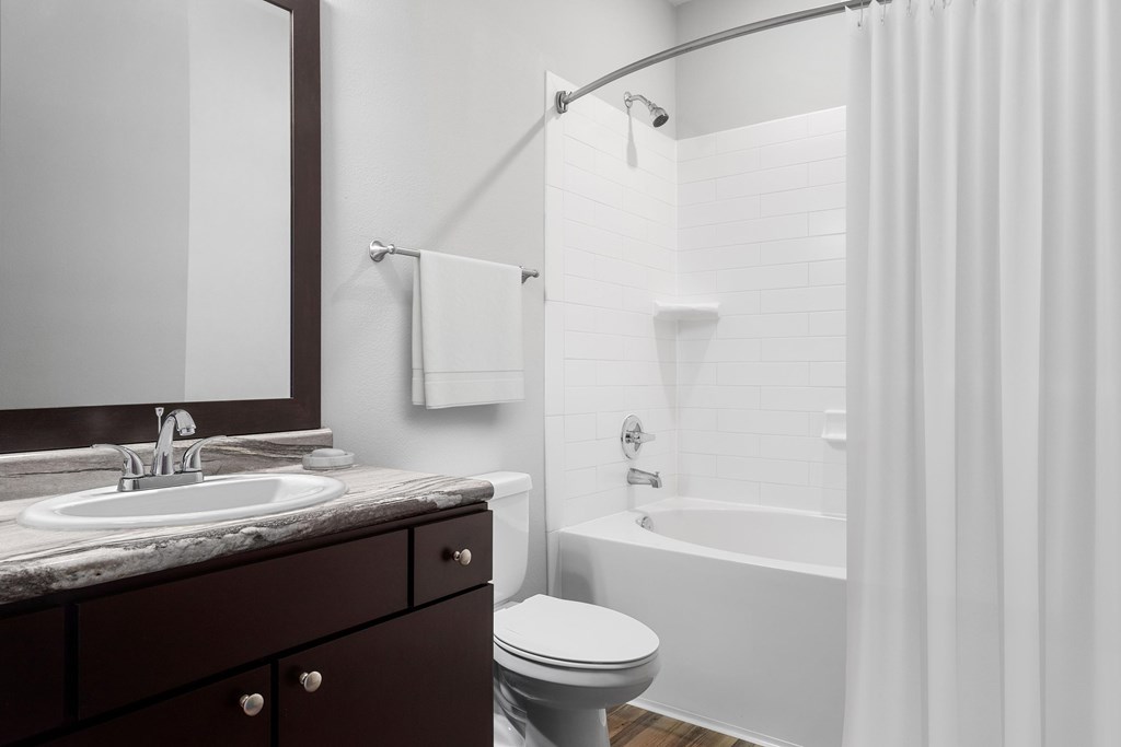 A bathroom with a white tub, sink, and toilet.