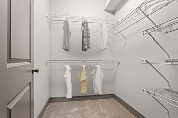A white closet with clothes hanging on shelves.