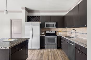 A kitchen with black cabinets and a granite countertop.