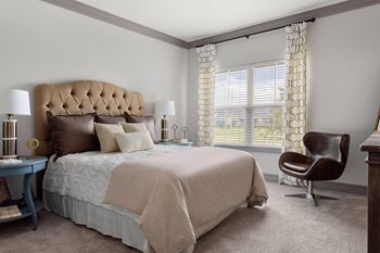 A bedroom with a large bed and a chair.