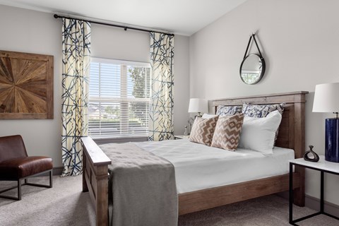 Bedroom with wooden furniture and patterned curtains at Adara Overland Park Apartments, Overland Park, Kansas