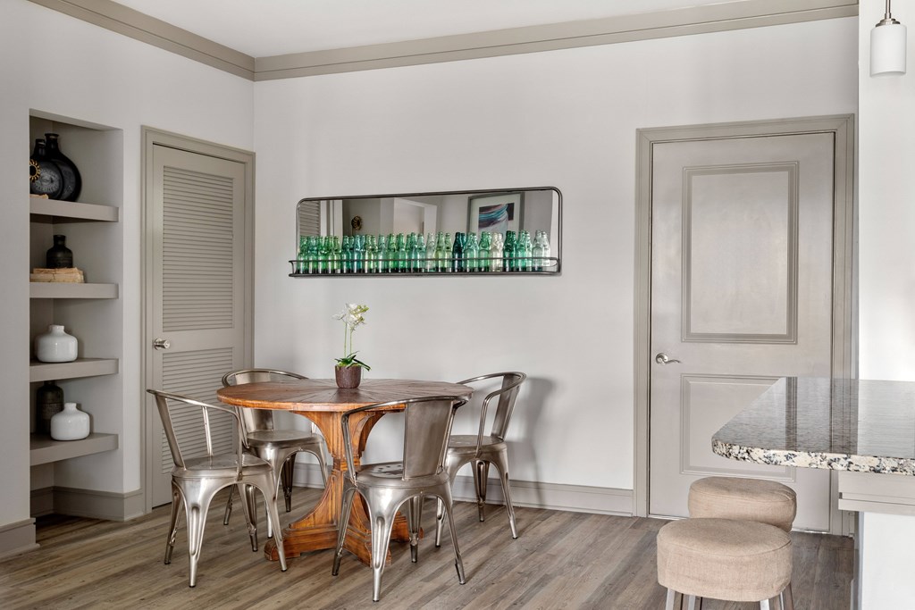 A dining table with chairs and a shelf with bottles on it.