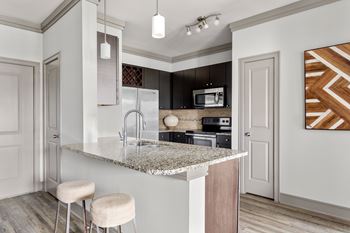 A kitchen with a marble countertop and a bar stool.