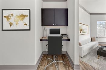 A black computer desk with a monitor and keyboard sits in a room with a world map on the wall.