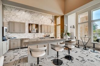 a kitchen with a marble counter top and a bar with chairs