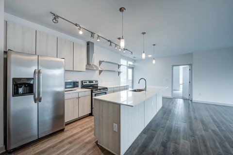 A modern kitchen with a stainless steel refrigerator and wooden flooring.