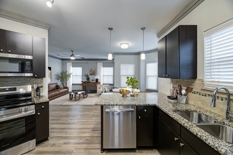 A modern kitchen with dark wood cabinets and stainless steel appliances.