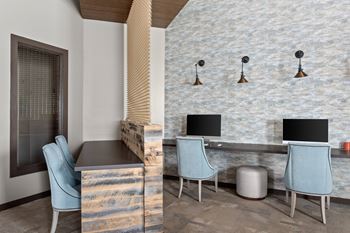 A room with a desk, chairs and a stone wall.