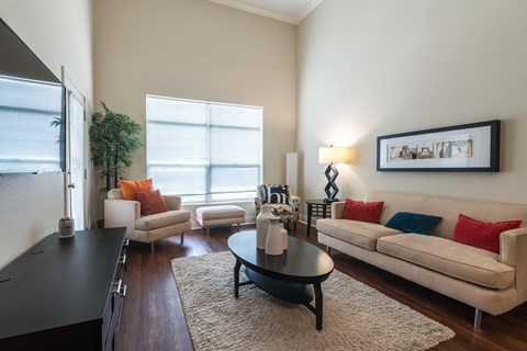 A living room with a black coffee table and a white couch with red and blue pillows.