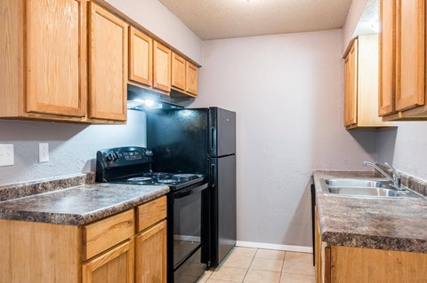 A kitchen with wooden cabinets and a black refrigerator.