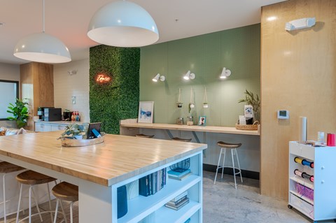 A modern kitchen with a wooden counter and white stools.