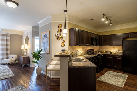 A kitchen with dark brown cabinets and a black refrigerator.