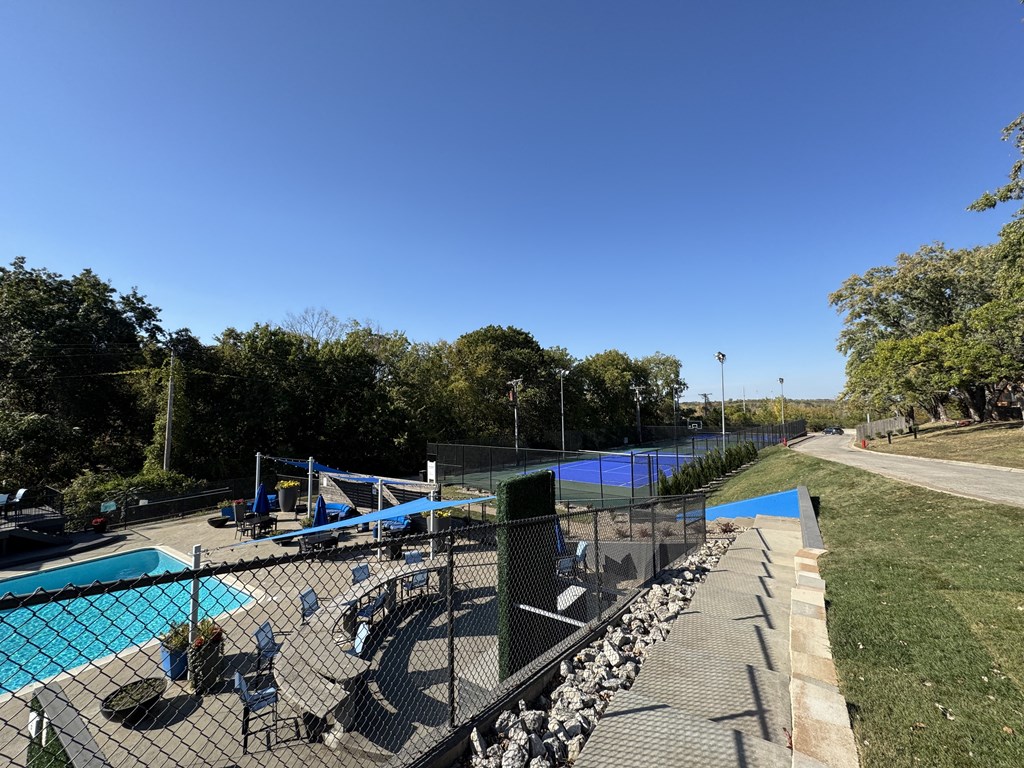 a view of a tennis court with a pool and a fence at The Boulevard, Roeland Park, KS