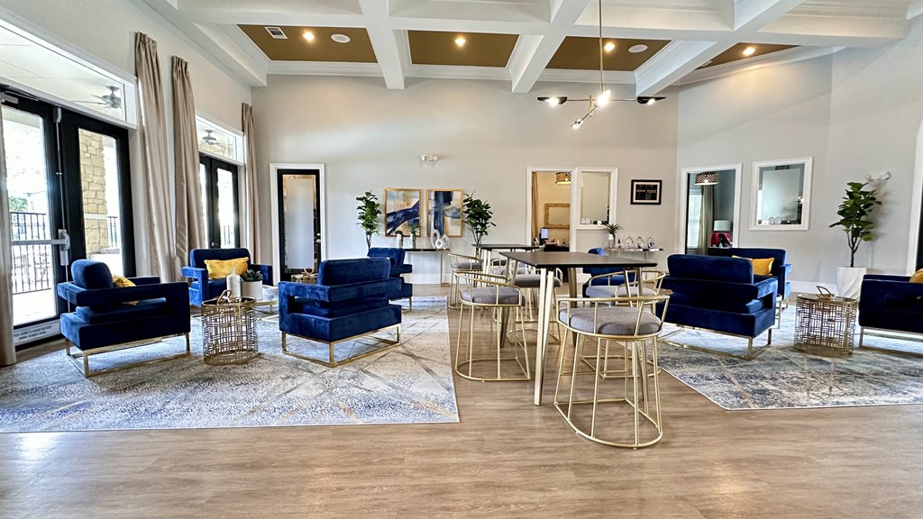 a living room with blue chairs and tables and a kitchen