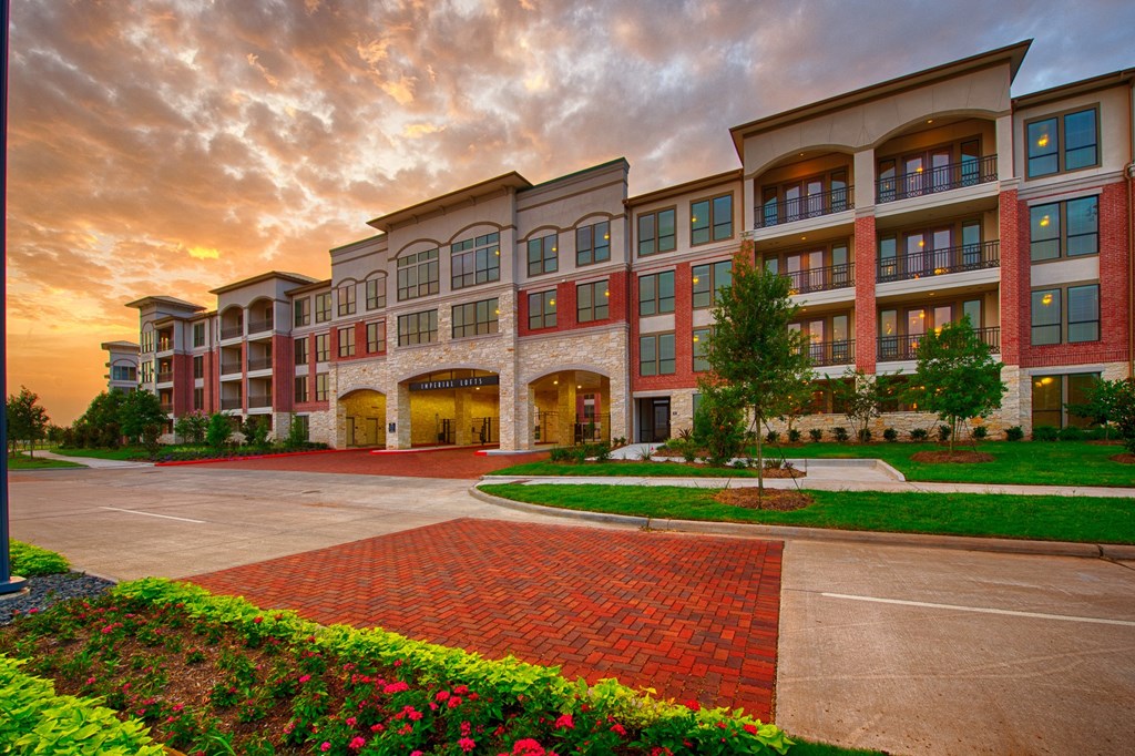 an exterior view of an apartment building at sunset at Imperial Lofts, Sugar Land, 77498