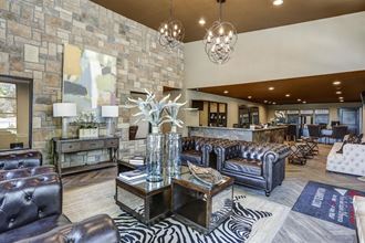 a living room with leather furniture and a large stone wall