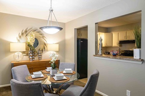 A modern dining room with a glass table and grey chairs.
