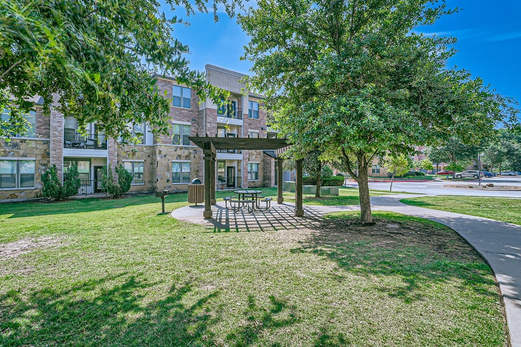 a park with trees and a picnic area in front of a building at Discovery at Craig Ranch, Texas, 75070