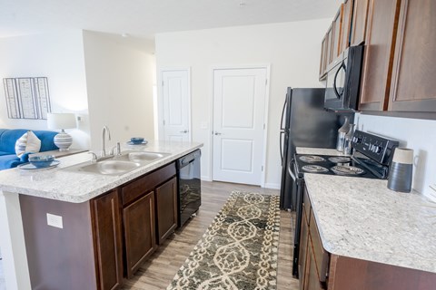 A kitchen with a black refrigerator and a white counter top.