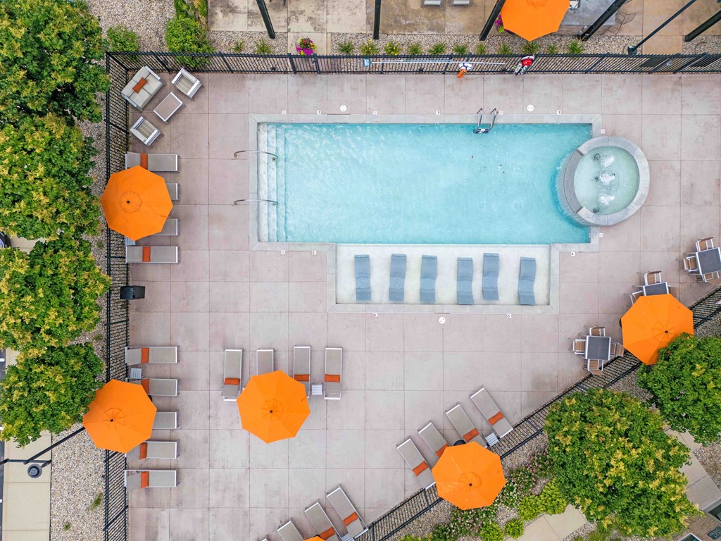 An aerial view of a pool surrounded by orange umbrellas and chairs.