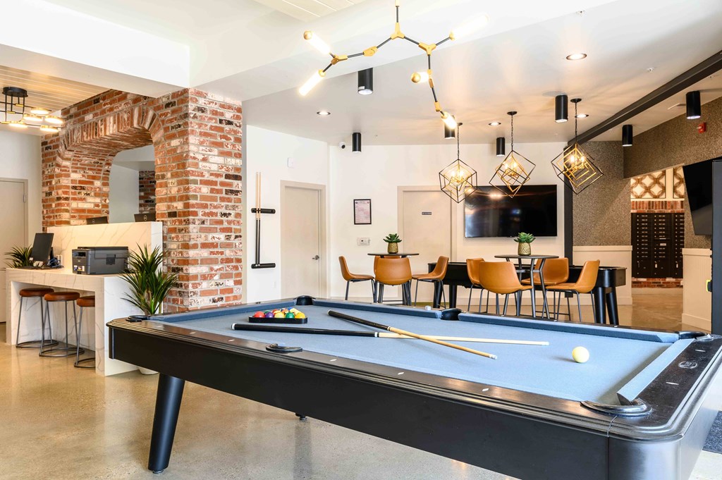 A pool table is in the middle of a room with a brick archway and a bar area.