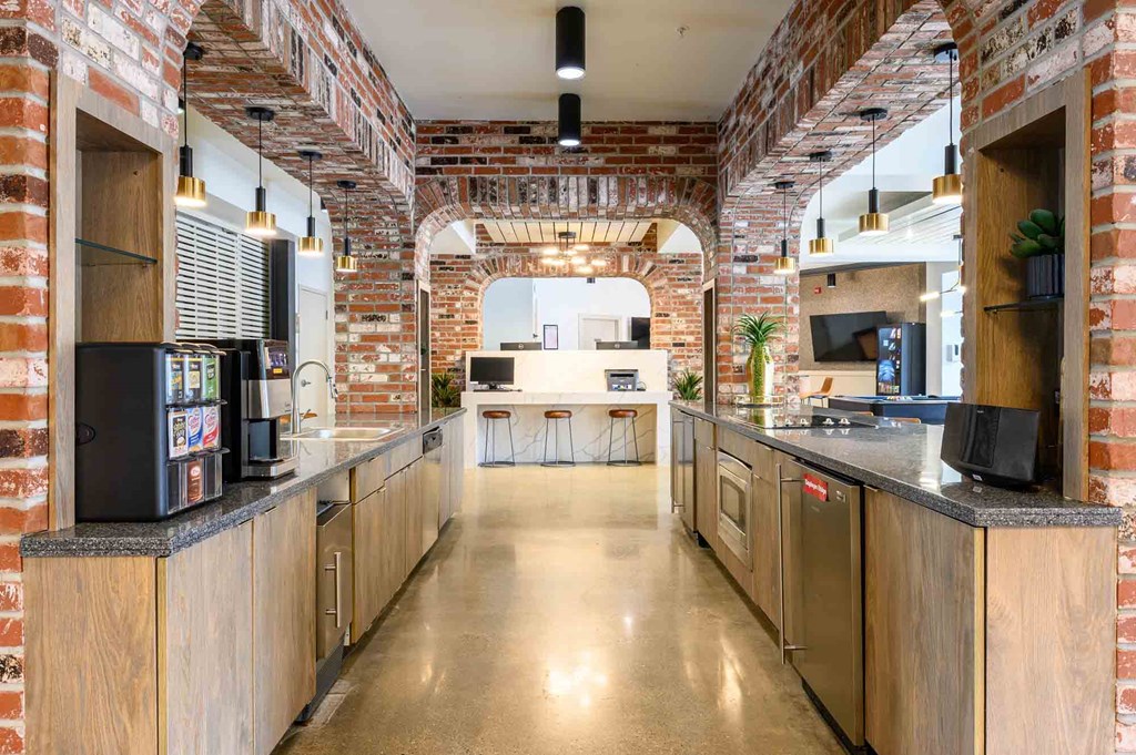 A kitchen with a brick wall and wooden cabinets.