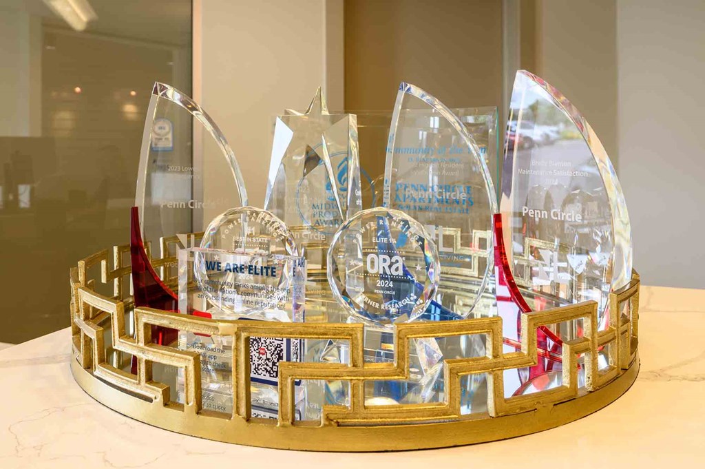 A glass trophy with a red ribbon is placed on a gold base.