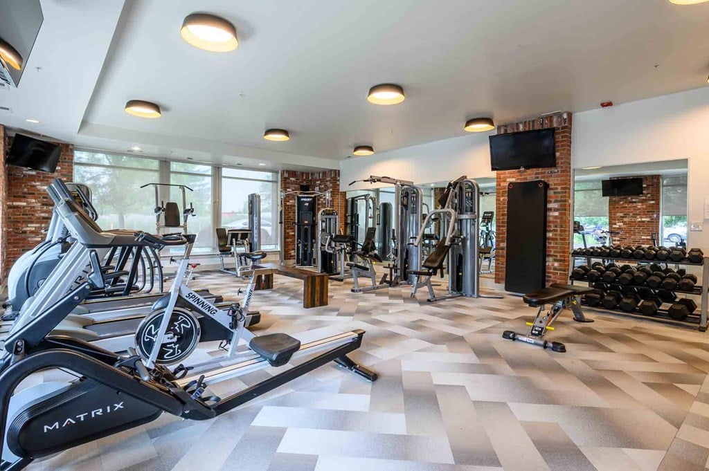 A gym with a variety of equipment including treadmills, weights, and exercise machines.
