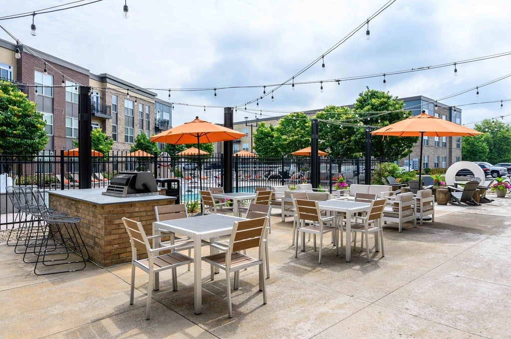 A patio with tables and chairs under orange umbrellas.