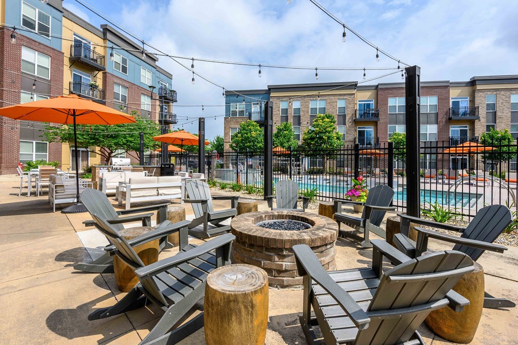 A patio with chairs and tables is surrounded by apartment buildings.