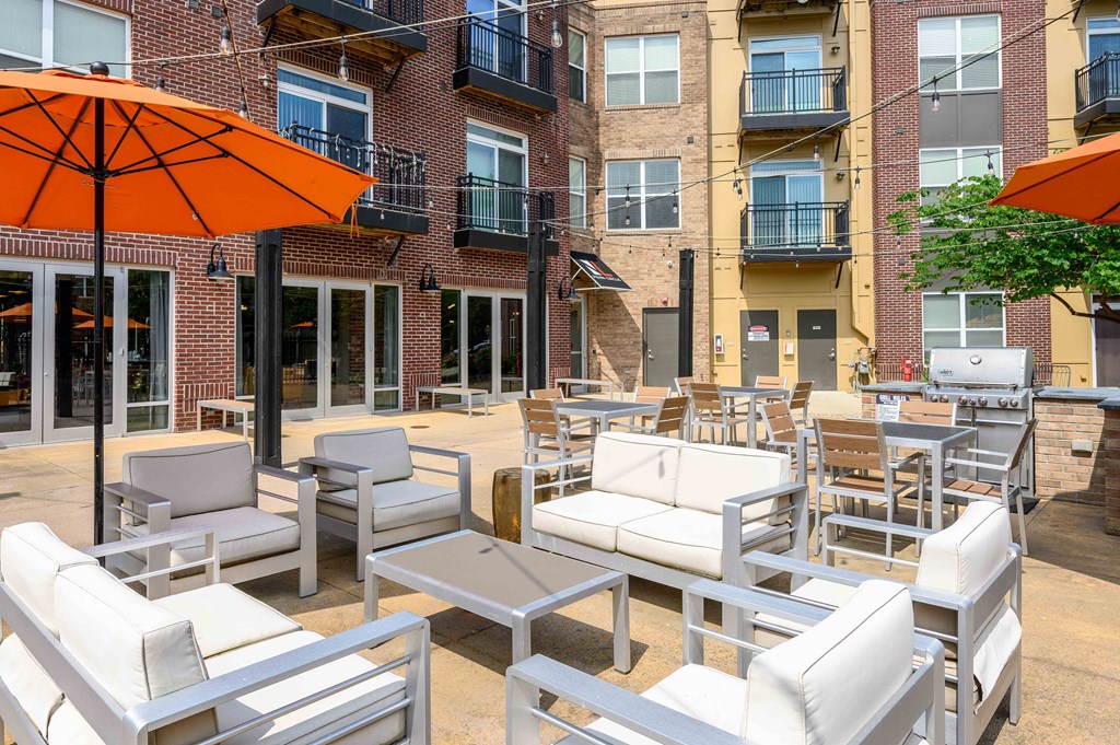 A patio with white furniture and orange umbrellas.